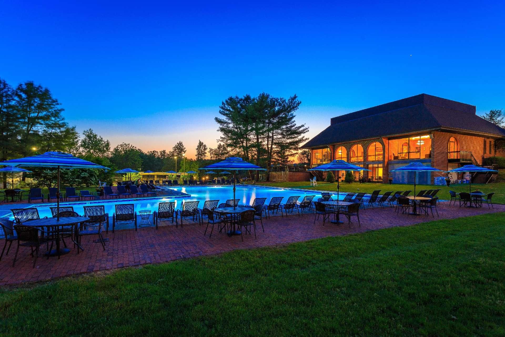 In-ground L shaped pool surrounded with brick patios. Variety of tables, umbrellas, & 椅子.